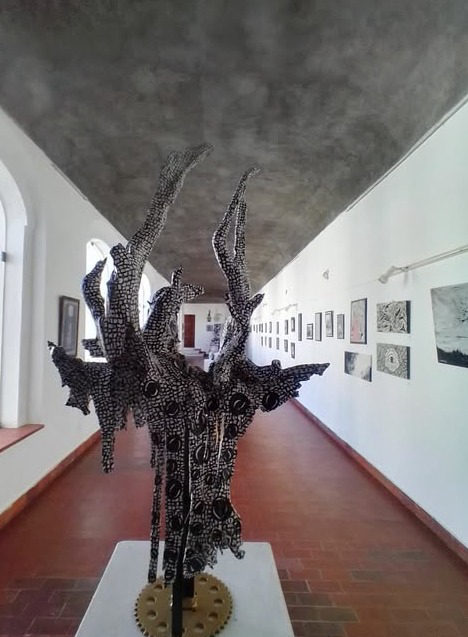 Escultura em raiz de eucalipto pintada a acrílico, instalada num corredor expositivo