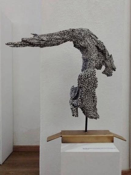 Escultura horizontal em raiz de eucalipto, sobre plinto, em sala expositiva
